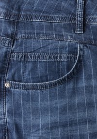 Tmavě modré džíny z denimu s jemným pruhem, zadní kapsou s oblémi tvarem a jedním detailem kovového knoflíku.