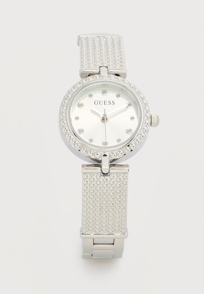 Ασημένιο ρολόι χειρός Guess με στρογγυλό καντράν, κρύσταλλινα σημάδια ωρών, υφασμένη στεφάνη και μπρασελέ, και τρία ασημένια δείκτες που δείχνουν 9:10:30.