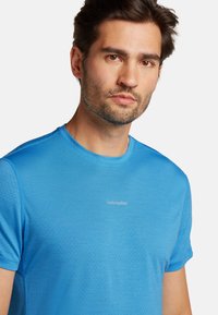 Blå kortærmet t-shirt lavet af tekstureret stof, med et lille logo på brystet. Rund halsudskæring, regulær pasform.