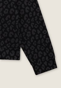 Manica di felpa nera con un motivo a leopardo scuro. Orlo a polsino e texture morbida. Logo "Freddy" visibile in modo sottile.