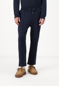 Marineblauwe sweatpants met een trekkoord in de taille, zakken aan de zijkanten en een structuurstof. Heeft rechte pijpen en subtiele stiksels aan de voorkant.