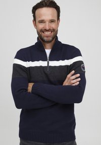 Mornarski pleteni pulover s bijelim i sivim horizontalnim prugama, ovratnik na pola zatvaranja, rebrasti manžeti i rub, oznaka brenda na lijevom rukavu.