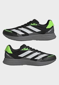 Scarpe da corsa nere leggere con strisce bianche e dettagli verdi. Parte superiore in mesh, suola ammortizzata e dettaglio testurizzato sul tallone.