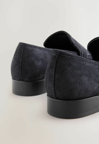Scarpe slip-on in suede blu navy con suola in gomma nera opaca. Il design presenta una texture liscia con dettagli di cucitura discreti sul tallone.