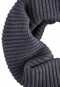 Scrunchie lavorato a maglia di colore grigio scuro con una texture a coste, caratterizzato da una forma circolare e un aspetto morbido. Realizzato in un materiale simile alla lana.