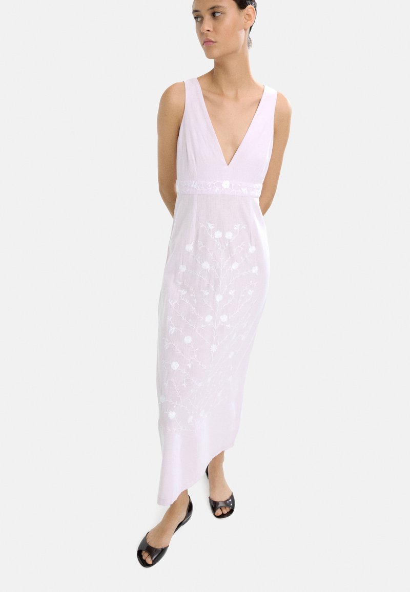 Jasnoróżowa sukienka bez rękawów z głębokim dekoltem w kształcie litery V, ozdobiona haftem kwiatowym wzdłuż spódnicy. Gładka tekstura, długość do kostek z lekko asymetrycznym dołem.