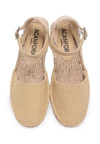 Beżowe espadryle z tkaniny o otwartym designie pasków. Naturalna, pleciona tekstura, okrągły nosek i gumowa podeszwa. Posiadają regulowane klamry.