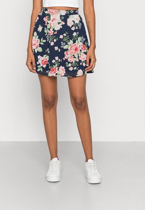 Saia floral com fundo azul-marinho, rosas cor-de-rosa e folhas verdes. Feita de tecido leve, com forma evasê e cintura elástica.