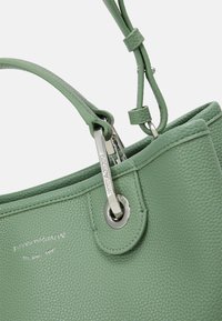 Zielona skórzana torebka o fakturowanej powierzchni, z srebrnymi elementami metalowymi i odpinanym paskiem, oferująca różnorodne możliwości noszenia.