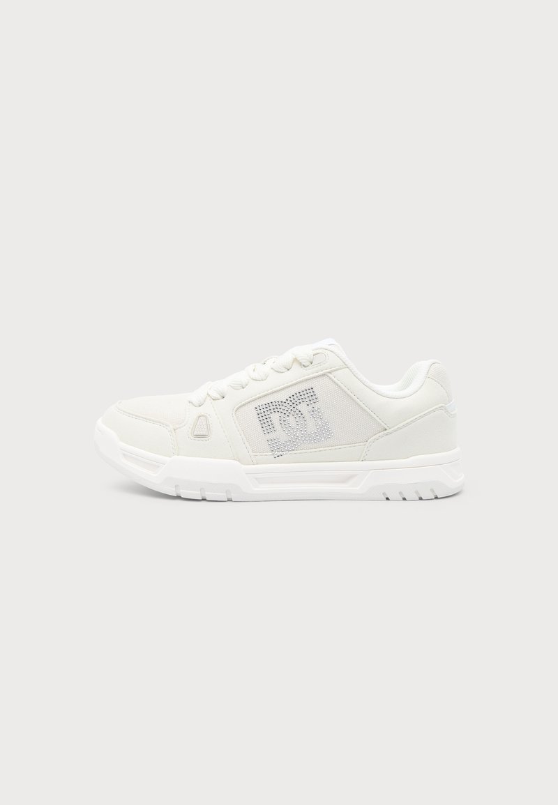 Baskets basses blanches avec un design à lacets et une semelle texturée, comptant un panneau de logo perforé sur le côté.