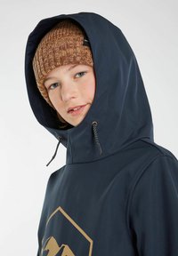 Giacca con cappuccio blu navy con una grafica dorata di montagne, realizzata in materiale liscio e resistente alle intemperie. Presenta stringhe regolabili. Berretto in maglia marrone caldo.