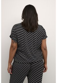 Blusa a maniche corte con motivo in bianco e nero, dalla vestibilità ampia, con un design a onde. Tessuto morbido con scollatura rotonda e maniche arrotolate.