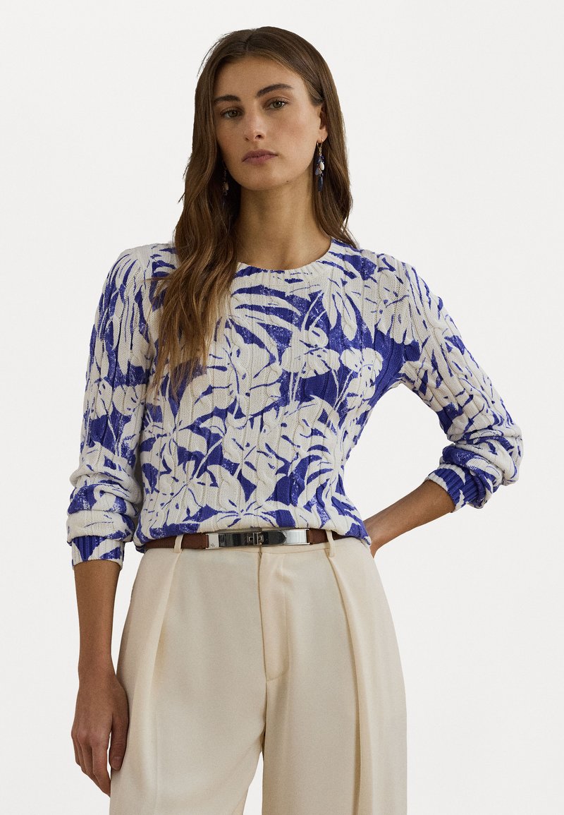 Knit sweater featuring a blue and white botanical pattern, crew neck, and ribbed cuffs, paired with high-waisted beige trousers and a belt.