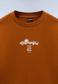 Καφέ βαμβακερό t-shirt με στρογγυλή λαιμόκοψη, κοντά μανίκια και λευκό τυπωμένο λογότυπο με γραφικό ήλιο και κείμενο με σύνθημα.