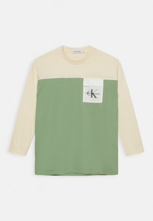 Skjorte med lange ærmer med beige øverste del og ærmer, grøn nederste del og en hvid brystlomme med Calvin Klein Jeans-logo.