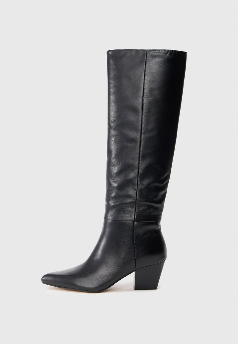 Botte en cuir noire à hauteur de genou avec un bout pointu et un talon épais de hauteur intermédiaire, présentée sur un fond clair uni.