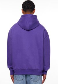 Paarse hoodie met een relaxed-fit, gemaakt van een soepele stof. Bevat een kangoeroezak en geribde manchetten.