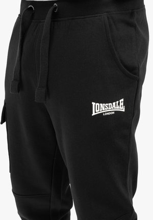 Sorte sweatpants i bomuldsblanding med elastisk talje, snøre, sidelommer og hvid broderet logo "Lonsdale London" på låret.