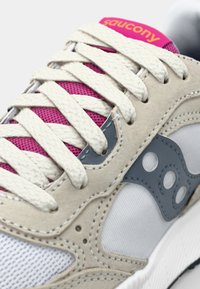 Baskets comportant un dessus en daim beige, des accents gris, un mesh blanc, une languette en mesh rose et des lacets crème, avec une semelle en caoutchouc texturée.
