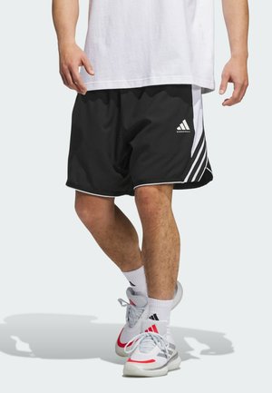 Black athletic shorts with white accents and three stripes design, made of lightweight material, paired with gray and red sneakers.