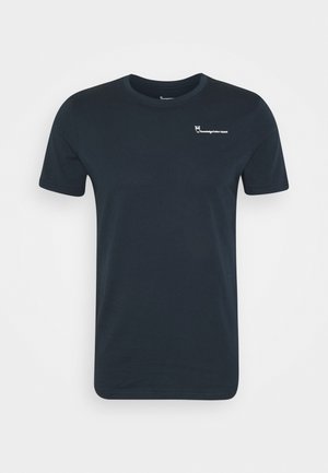 Schwarzes T-Shirt mit kurzen Ärmeln, Rundhalsausschnitt, kleinem weißem Eulenlogo und der Aufschrift "Knowledge Cotton Apparel" auf der linken Brust.