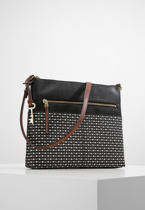 Sac bandoulière à motif noir et blanc avec une lanière en cuir marron, une poche zippée et un porte-clés doré suspendu sur le côté.