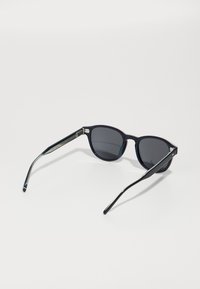Ochelari de soare negri cu lentile gri, rame rotunde și brațe metalice subțiri cu un design texturat. Culoare de accent pe mânere.