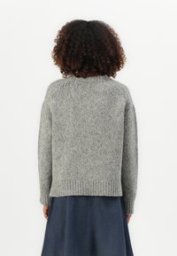 Gray knit sweater with a rounded neckline, ribbed cuffs, and hem. The fabric has a textured, soft appearance. Model wears a dark blue skirt.