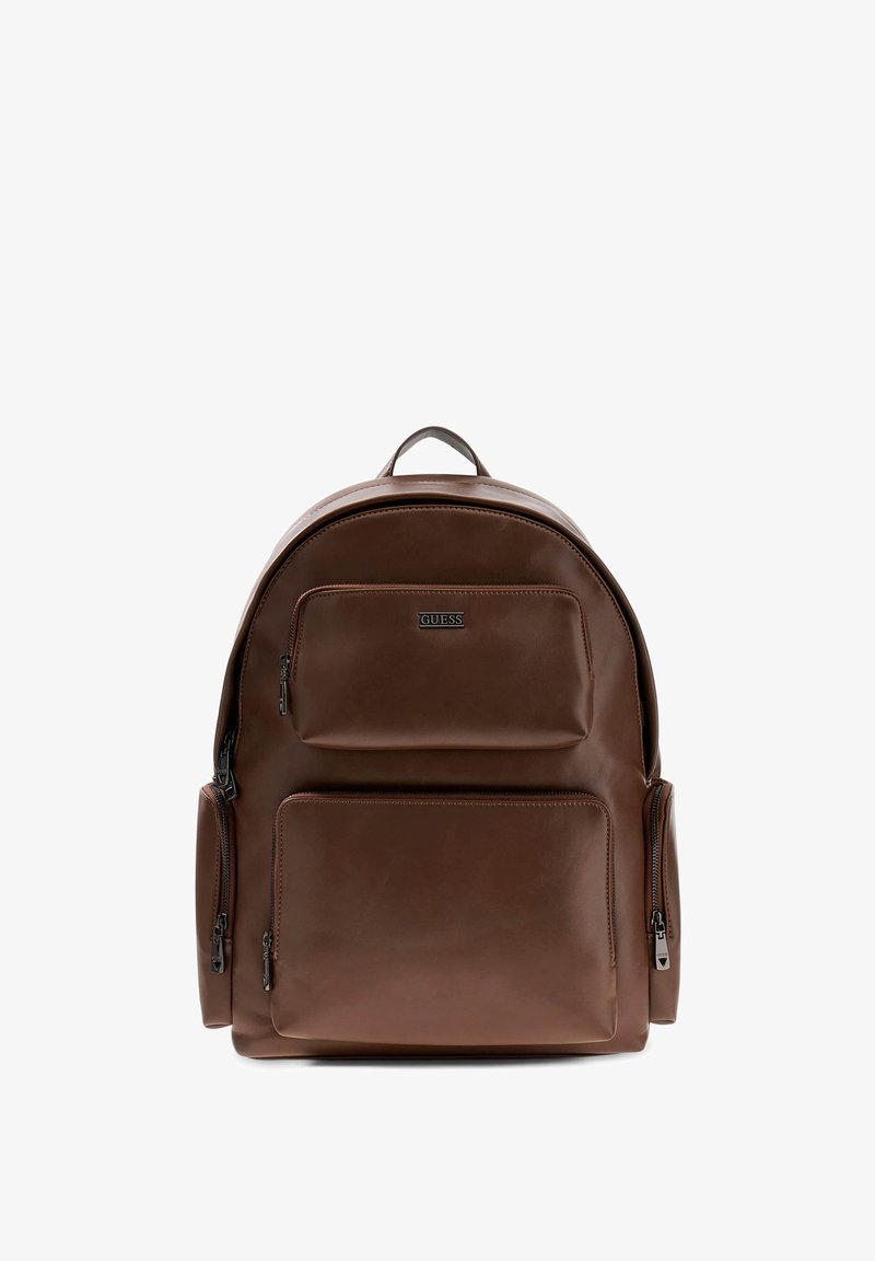 Zaino in pelle marrone dalla forma arrotondata. Presenta un manico superiore, diverse tasche con zip e una texture liscia con un branding sottile.