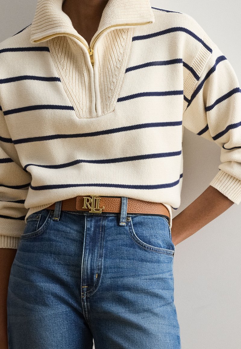 Person wearing a cream and navy striped knit sweater with a zip collar, blue jeans, and a brown leather belt with a gold RL buckle.