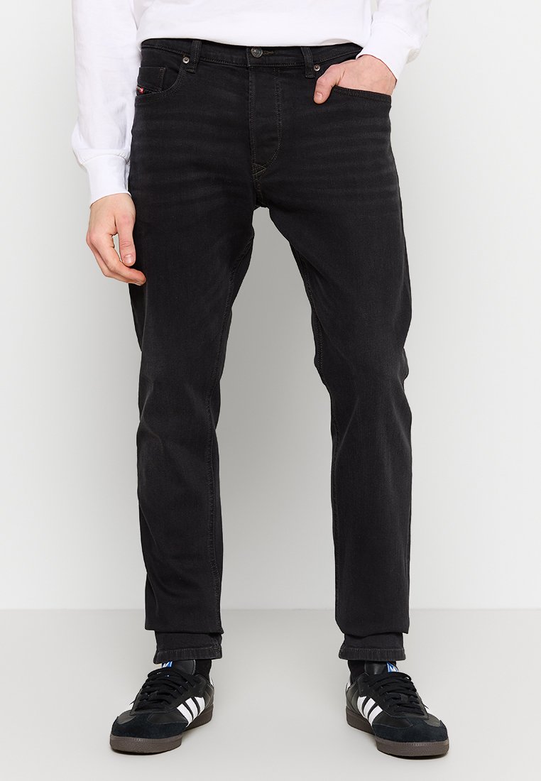 Jean noir à coupe droite, en denim. Présente une texture délavée, un design à cinq poches et un logo discret à l'arrière.