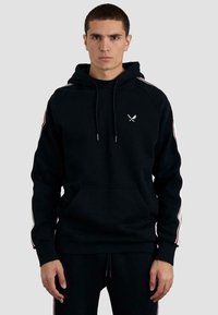 Sudadera negra con capucha, bolsillo frontal, rayas contrastantes a lo largo de las mangas y un pequeño emblema blanco en el pecho.