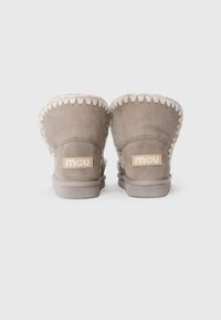 Stivaletti alla caviglia in suede grigio con fodera in shearling, caratterizzati da cuciture decorative lungo il bordo superiore e una suola piatta in gomma.