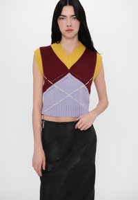 Utenermet strikket topp med v-hals, i sterke farger med blokker i maroon, gul og lavendel, med geometriske mønstre og ribbede kanter.