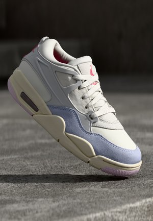 Valkoinen ja vaaleansininen Air Jordan -lenkkari, jossa on vaaleanpunaisia korostuksia, näkyy ilmassa harmaan betonitaustan edessä.