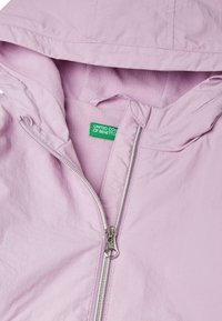 Giacca a zip di colore rosa chiaro con cappuccio, dotata di interno in pile, zip argentata e etichetta verde con la scritta "UNITED COLORS OF BENETTON."