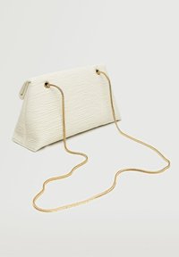 Biała torebka o fakturze i trójkątnym kształcie, ze złotym łańcuszkiem oraz metalowymi oczkami do mocowania paska.