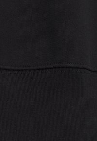 Tela de sudadera negra con una textura suave y detalles acanalados. Presenta costuras limpias a lo largo del dobladillo.