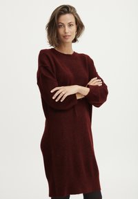 Abito lavorato a maglia oversize in bordeaux con maniche lunghe, scollo a giro e una texture morbida, che arriva a metà coscia, dal design accessibile.