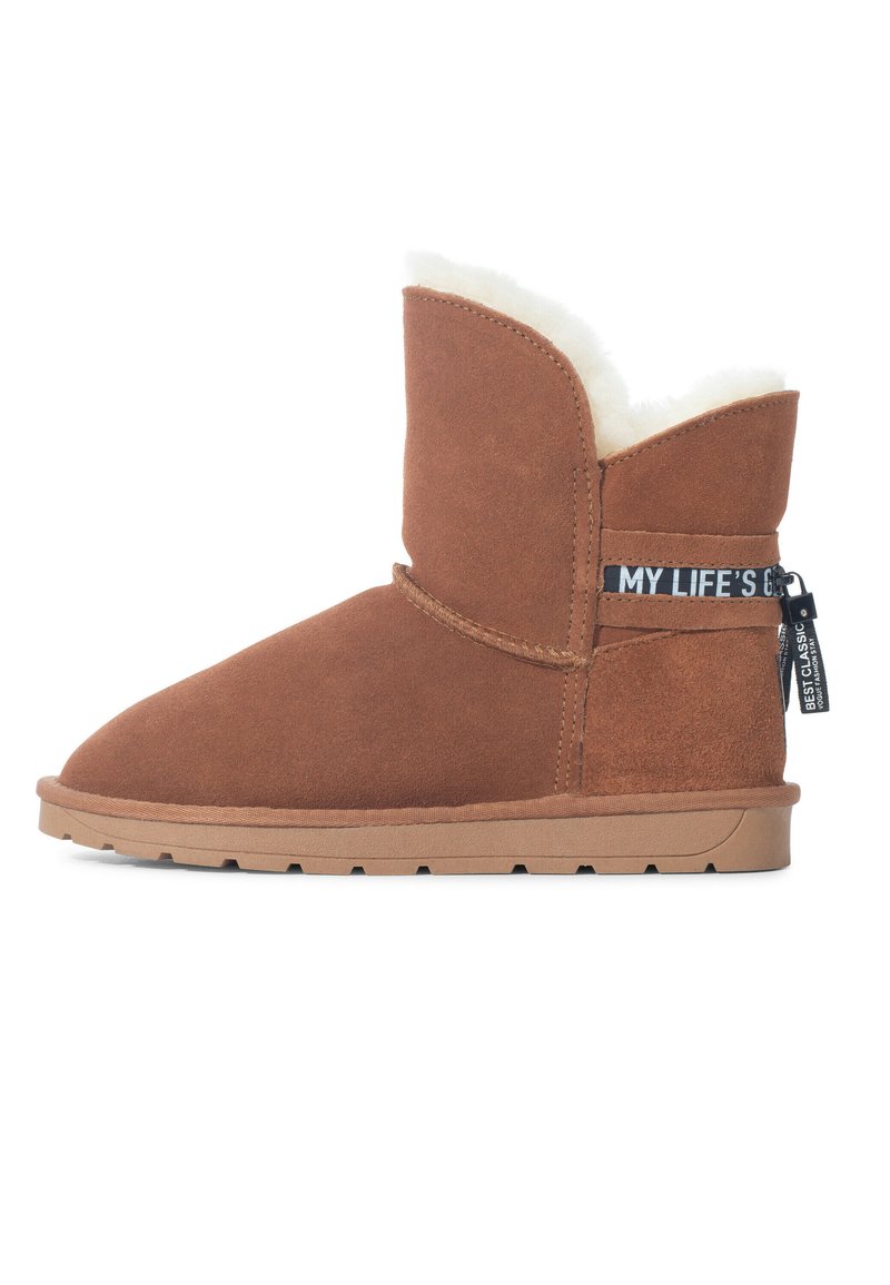 Botas de tobillo de ante marrón con un suave forro blanco, con una altura corta, superficie texturizada y una etiqueta lateral con detalles de la marca.
