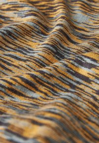 Strickstoff mit wellenförmigen Streifen in Orange, Grau und Dunkelbraun. Weiche Textur mit einem dezenten Muster, das einen geschichteten visuellen Effekt erzeugt.