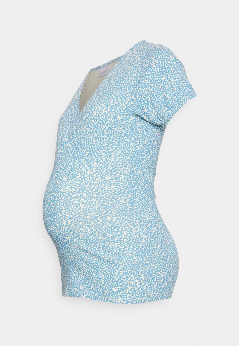 Top de maternidade de manga curta em azul claro com padrão salpicado branco, apresentando um decote em V e uma silhueta ajustada.