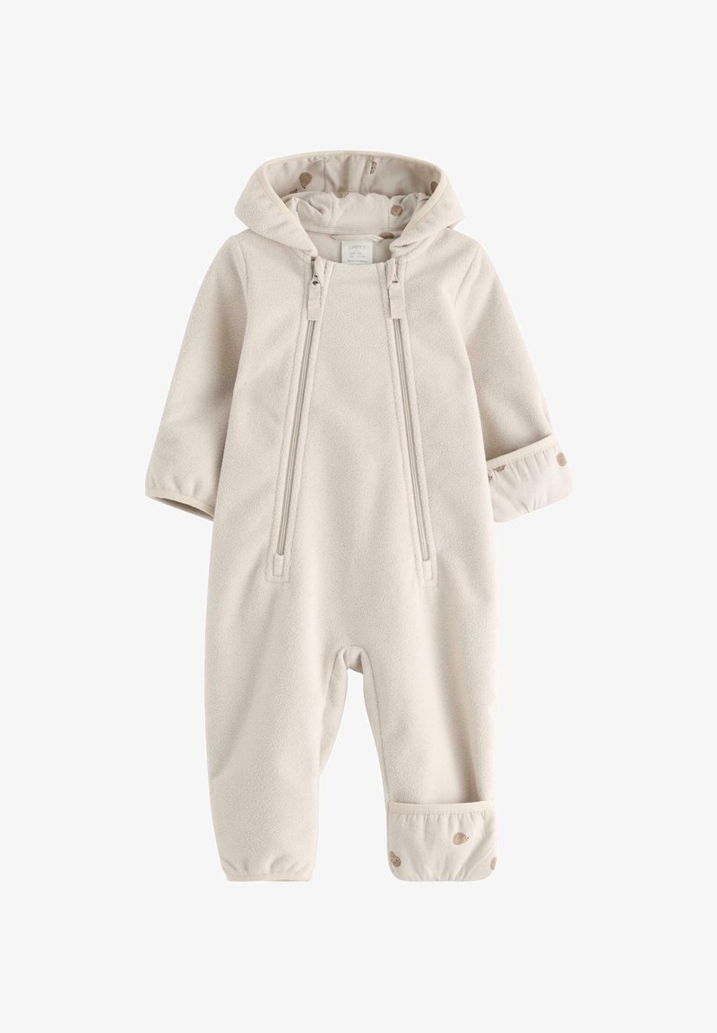 Jasno beżowy polarowy kombinezon z kapturem, dwoma przednimi zamkami błyskawicznymi, elastycznymi mankietami i wzorzystą podszewką z złotymi akcentami. Miękka tekstura.