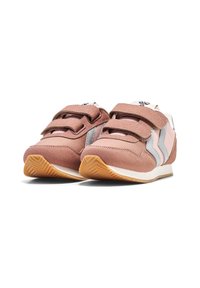 Baskets en daim rose avec des bandes velcro, accents blancs et gris, et une semelle en caoutchouc présentant un motif texturé en chevrons.