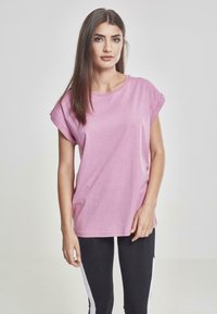 T-shirt rosa a maniche corte realizzato in cotone, con scollatura rotonda e maniche arrotolate, abbinato a leggings neri con strisce laterali bianche.
