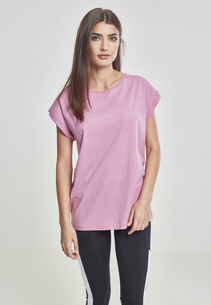 T-shirt rosa a maniche corte realizzato in cotone, con scollatura rotonda e maniche arrotolate, abbinato a leggings neri con strisce laterali bianche.