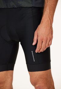 Schwarze Radshorts aus glattem, dehnbarem Material, mit einer engen Passform und einem weißen "ENDURANCE"-Logo an der Seite.