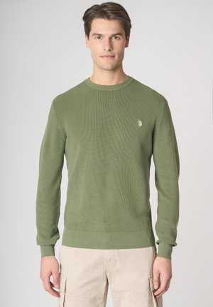 Maglione a coste verde con scollo rotondo e maniche lunghe. Presenta un piccolo logo sul petto e un orlo inferiore attillato.