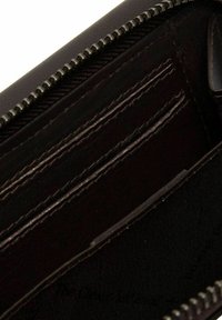 Interno del portafoglio marrone con più scomparti per carte, chiusura con zip e fodera in tessuto liscio. Presenta un esterno in pelle testurizzata.