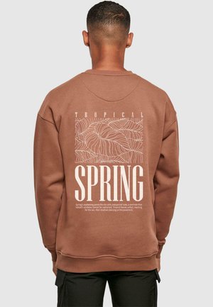 Brauner Sweatshirt mit einem weißen tropischen Blattgrafik und Textdesign auf der Rückseite. Hergestellt aus glattem Stoff mit Rundhalsausschnitt und gerippten Bündchen.